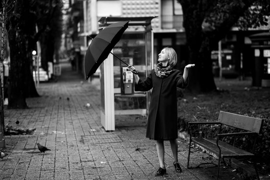 A woman standing with an umbrella. Black and white photo.
