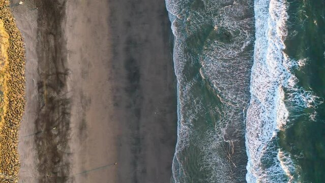 Slow Pan Rightward, Beach-to-Ocean, Vertical Aerial Shot Looking Straight down at Pacific Ocean Beach at Rockaway Beach, Oregon, with Incoming Waves and an RC Car Making Tracks in a Strip of Magnetite