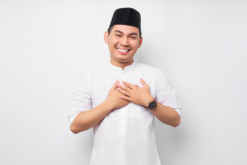 Excited young Asian Muslim man holding hands on chest and greeting welcoming Ramadan isolated on...