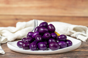Kalamata olive with blueberries flavor. Purple olives on wood background.