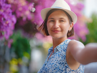 Blooming bougainvillea, streets of the old town of Bodrum, Turkey. Happy traveler woman in white elegant outfit walking by romantic streets . Summer travelling