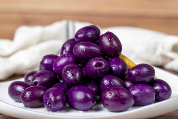 Kalamata olive with blueberries flavor. Purple olives on wood background. Close up
