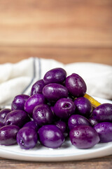 Kalamata olive with blueberries flavor. Purple olives on wood background. Close up