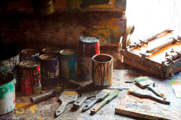 High angle view of paint cans with paintbrushes on wooden table