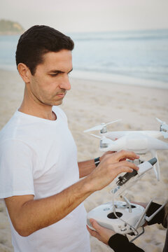 Man holding quadcopter while standing at beach
