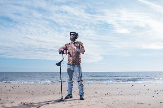 Full length of man looking away while resting arm on recreational metal detector at Horsey Beach