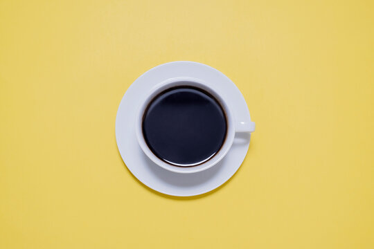 Overhead View Of Black Coffee In Cup On Yellow Table