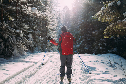 Rear view of man in ski-wear standing on snow covered road