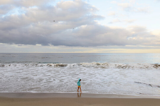 Girl walking at Laguna Beach against cloudy sky
