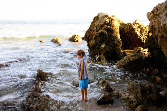 Side view of boy standing against rocks at Laguna Beach