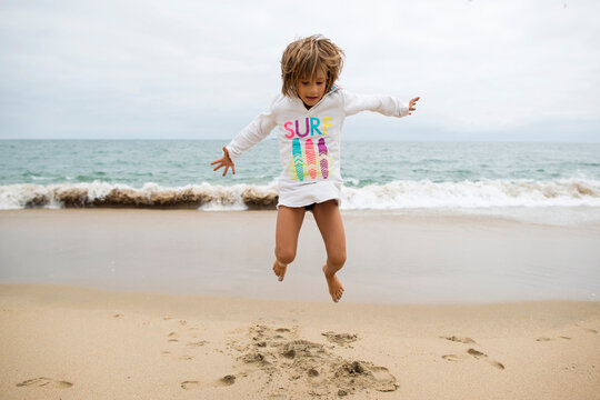 Playful girl jumping at Seal Beach against clear sky