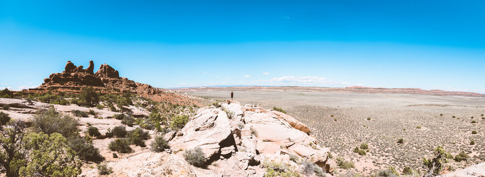Distant view of woman standing on rocky landscape against blue sky