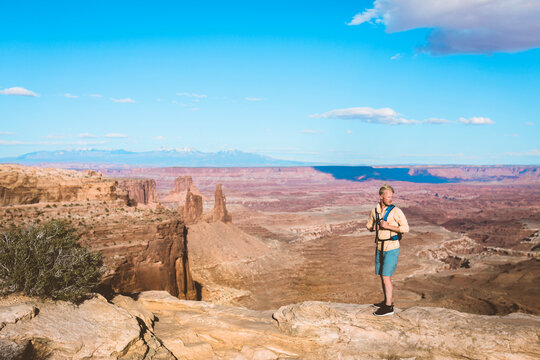 Full length of male hiker standing on mountain against blue sky