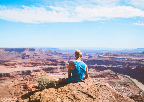 Rear view of male hiker looking at rocky mountains against sky