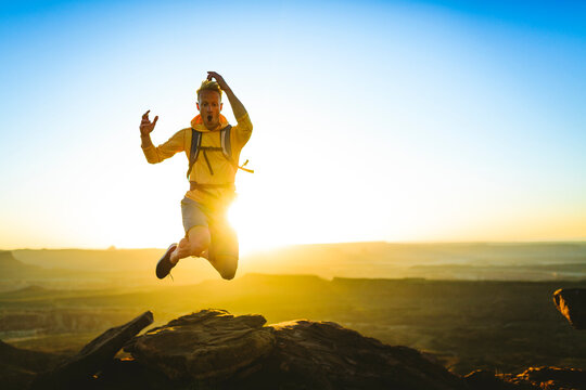 Excited hiker jumping on mountain at Canyonlands National Park