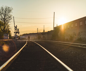 Rear view of man walking on railroad track during sunset