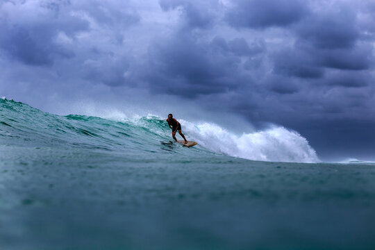 Man surfing on sea against stormy clouds