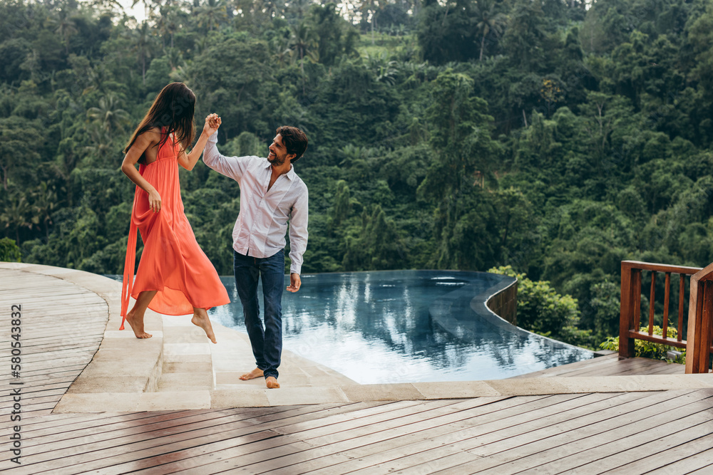 Wall mural Young couple near pool at resort