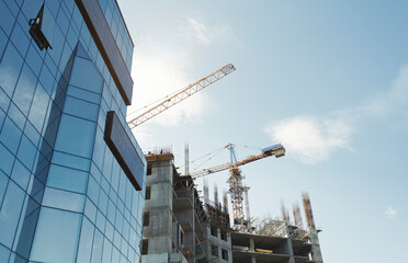 Low angle view of modern office building by construction site against sky in city