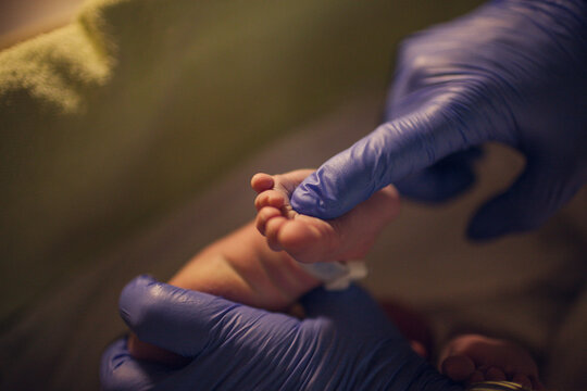 Cropped hands of pediatrician touching newborn baby's foot at hospital