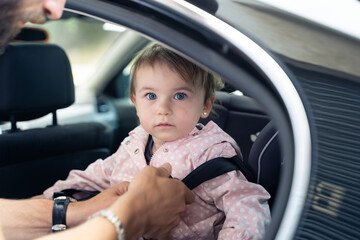 Father putting his daughter's seatbelt on in his car
