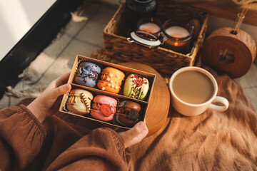 Box with different assortment of macaroons in hands