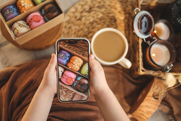 Girl taking a top-down photo of macaron box with various assortment using her phone