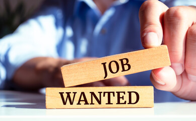 Close up on businessman holding a wooden block with "JOB WANTED" message