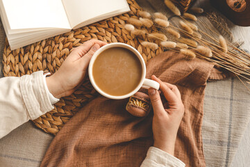 Cup of coffee in hands top view, macarons and open book, aesthetic photo