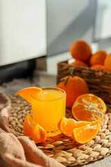 Glass of orange juice, sliced oranges, and a basket of oranges. The oranges are bright and fresh