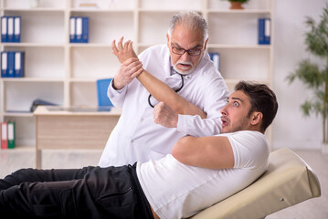 Fototapeta premium Young male doctor visiting old doctor chiropractor