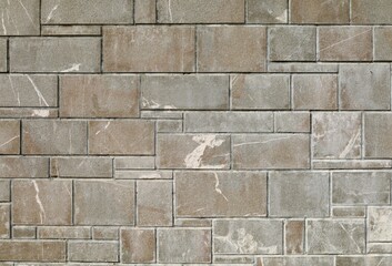 Exterior stone wall coating made by gray granite rock tiles of differen sizes. Background and texture.