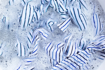 Top view of formal shirts soak in powder detergent water dissolution. Laundry concept