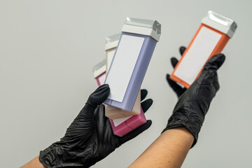 hand of a beautician holding fat-soluble wax cartridges for hair removal.