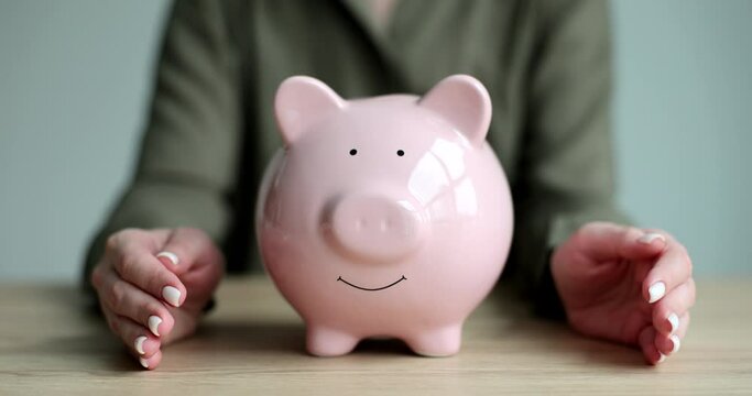 Woman hands hugging pink piggy bank with coins closeup 4k movie slow motion