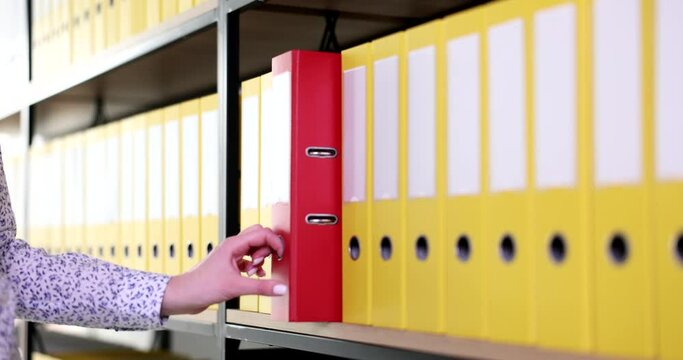 Female hand taking out red folder from shelf with yellow closeup 4k movie slow motion