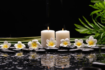 Spa still life with frangipani flowers, candle, long, leaves and zen stone - 580549689