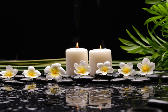 Spa still life with frangipani flowers, candle, long, leaves and zen stone