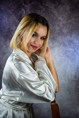 Fototapeta premium young slender blonde woman in a stylish dressing gown isolated on a beautiful background.