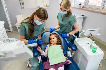 specialist dentist woman brushing the teeth of small child who was brought to the reception.