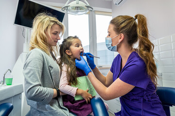 Little girl with her mom on visit their pediatric dentist