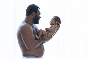 African American bearded father holding his cute newborn baby in his arms, Dad standing smiling and looking at baby, infant boy 2 months old, Family and newborn care. White background, side view