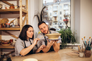 A happy young couple paints dishes at a pottery class