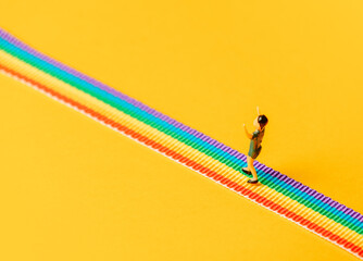 little boy figure stand on rainbow LGBT strip on yellow background