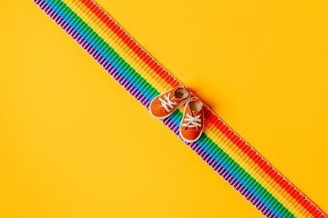 Little shoes on LGBT rainbow strip on yellow background