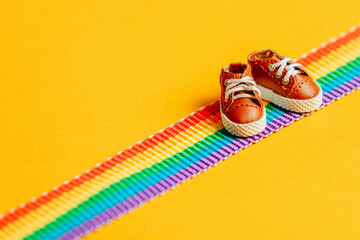 Little shoes on LGBT rainbow strip on yellow background