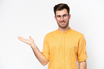 Young caucasian man isolated on white background holding copyspace imaginary on the palm to insert...