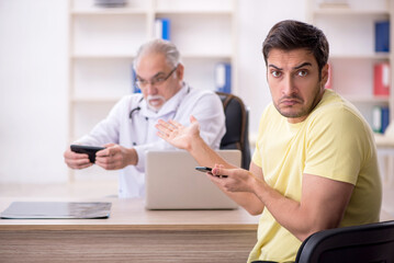 Obraz premium Young male patient visiting old male doctor