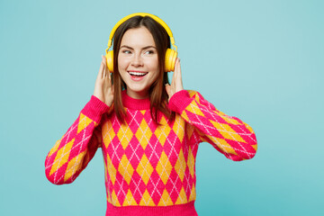 Young smiling happy fun woman wearing bright casual clothes headphones listening to music looking aside on area isolated on plain pastel light blue cyan background studio portrait. Lifestyle concept.