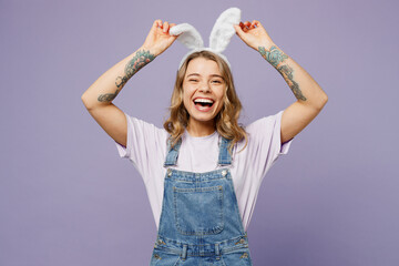 Young smiling happy woman wearing casual clothes hold show bunny rabbit ears laughing looking camera isolated on plain pastel light purple background studio portrait. Lifestyle Happy Easter concept.